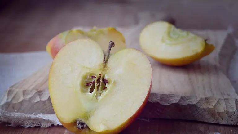 Sliced yellow apples on a wooden cutting board.