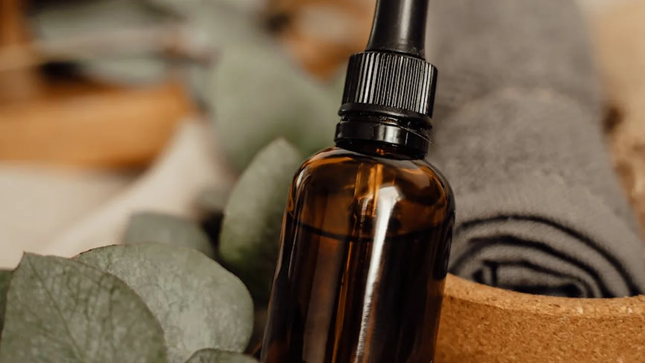 Brown glass dropper bottle of apricot kernel oil with a rolled towel in the blurred background.