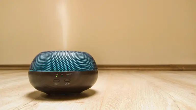 Round aroma diffuser with a blue mesh top on a light wooden floor