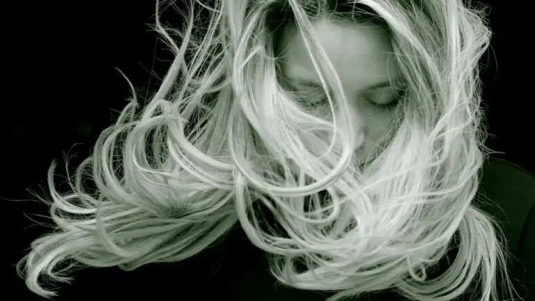 Black-and-white portrait of a woman with windswept hair covering her face