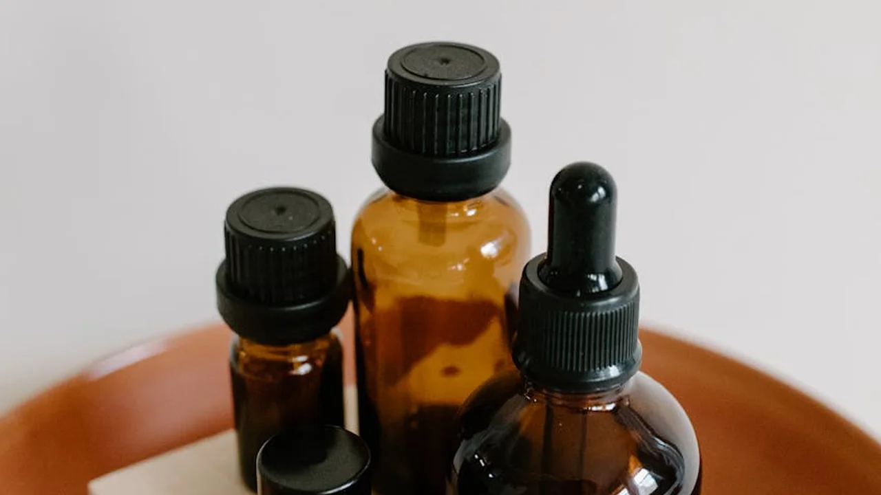 Amber glass bottles with droppers and caps on a wooden surface, used for making botanical oils at home
