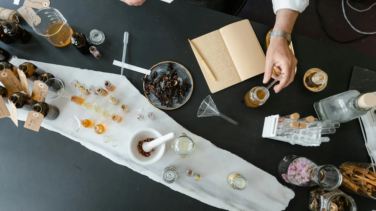 Top-down view of a dark table with numerous essential oil bottles, droppers, and a white cloth runner, representing a collection of botanical oils including tea tree oil.