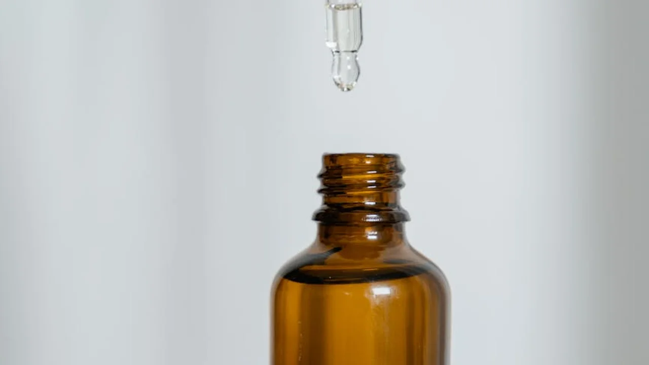 A brown glass bottle of castor oil with a dropper above a light background.