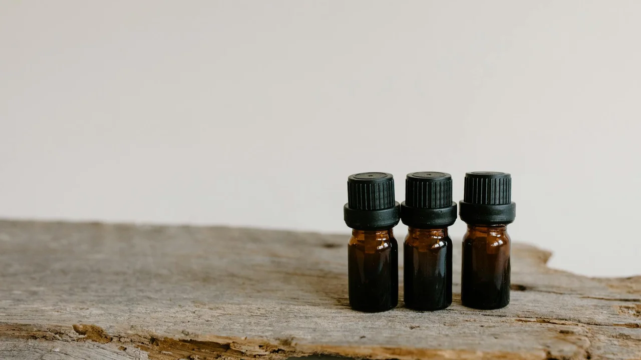Three amber glass bottles with black caps on a weathered wooden surface