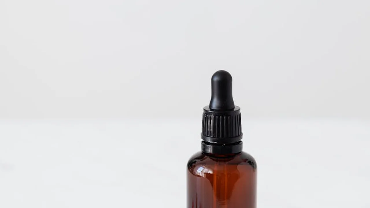 Brown glass dropper bottle of castor oil on a white background