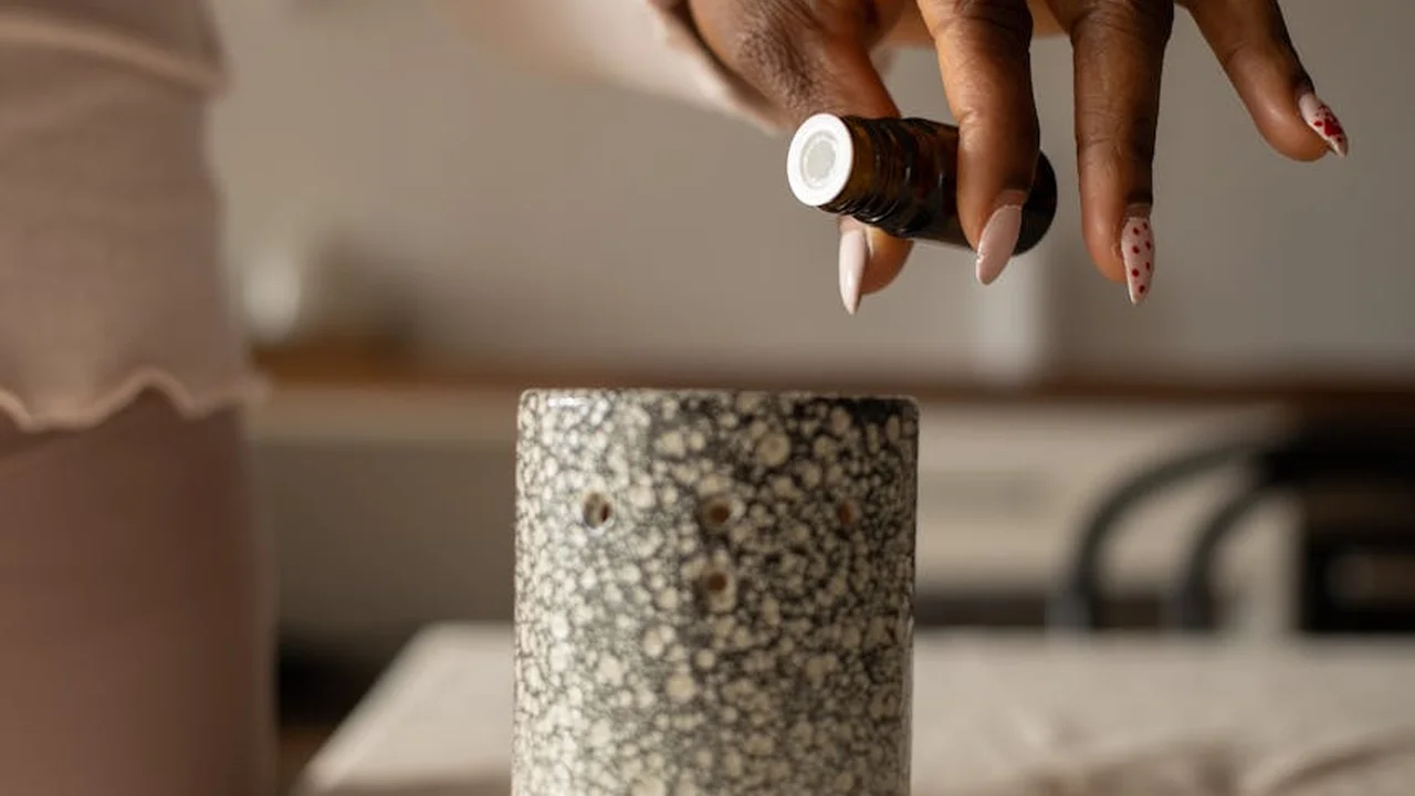 Close-up of a hand pouring castor oil from a small bottle onto a cloth, ready to prepare a castor oil pack.