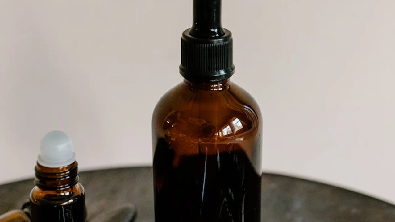 Amber glass bottle with a spray top and a small dropper bottle on a dark surface.