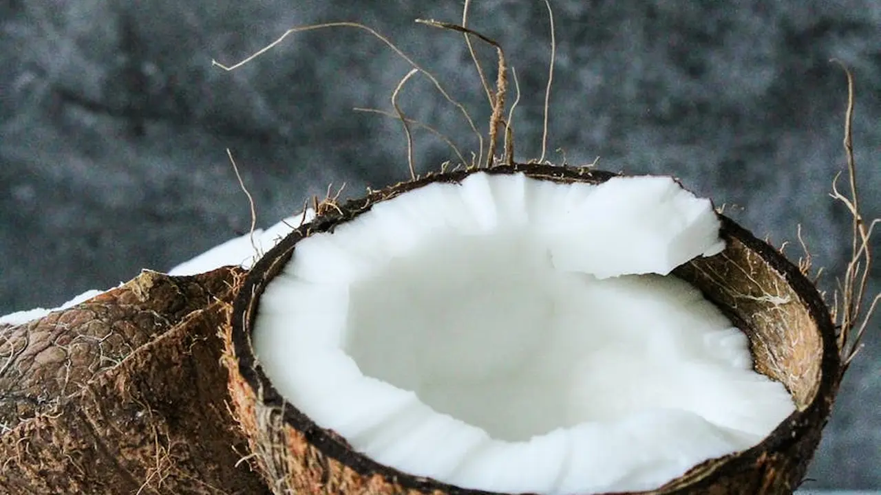 Close-up of a halved coconut with white coconut flesh against a dark background.
