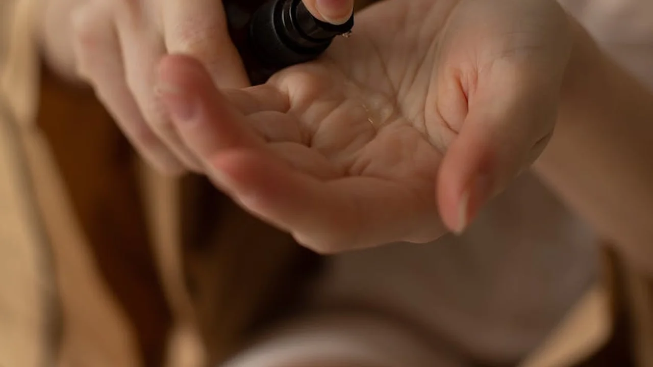 Close-up of hands cupping a skincare spray bottle, ready to dispense product for a facial oil and moisturizer layering routine