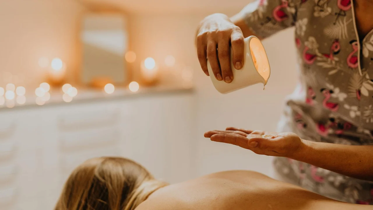 Close-up of a person holding a dropper over their open palm with a bottle of essential oil in a softly lit setting.