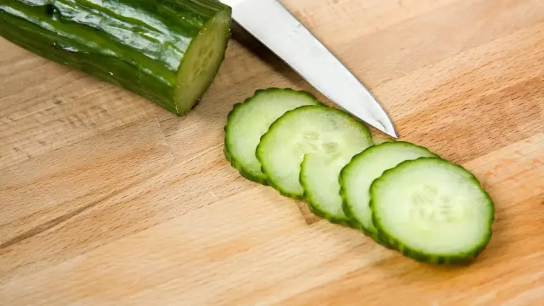 Sliced cucumber on a wooden cutting board with a knife