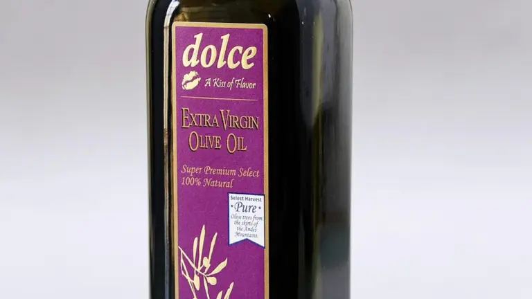 Close-up of a Dolce Extra Virgin Olive Oil bottle with a purple label on a light background