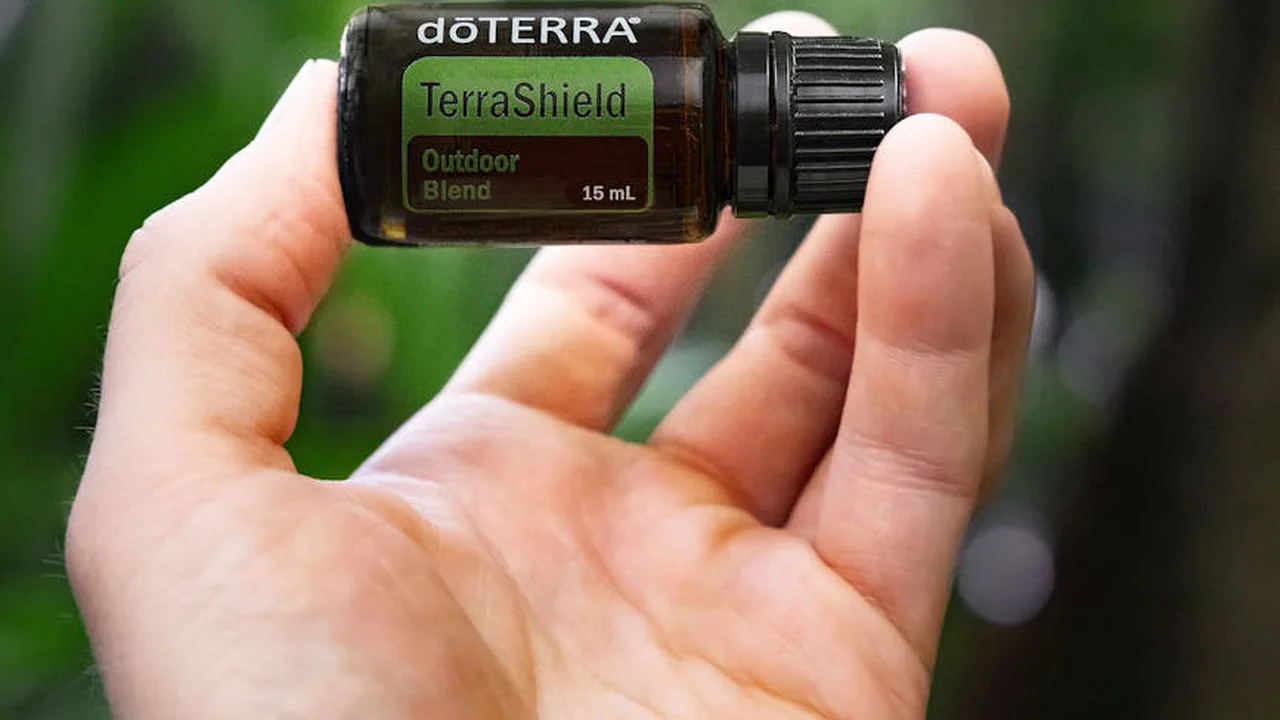 Close-up of a hand holding a small brown bottle labeled doTERRA TerraShield Outdoor Blend (15 mL).