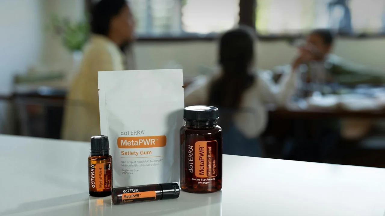 doTERRA MetaPWR essential oil products arranged on a white surface with blurred people in the background.