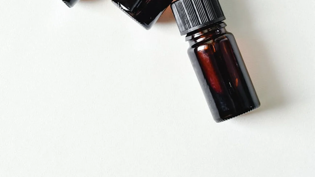 Two dark amber essential oil bottles resting on a white surface