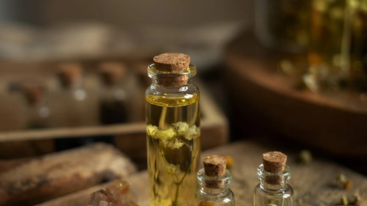 Small glass bottles with cork stoppers containing essential oils on a wooden surface, with a blurred background.