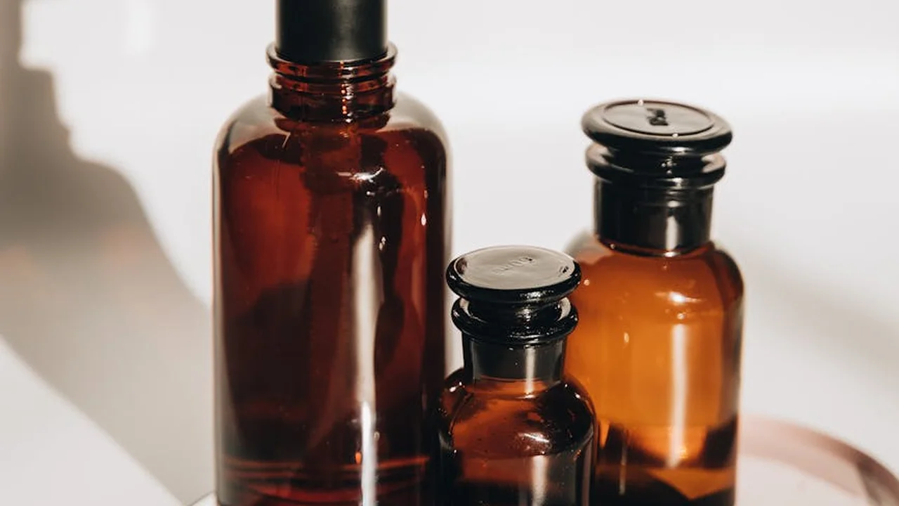 Three amber glass essential oil bottles with droppers on a white surface