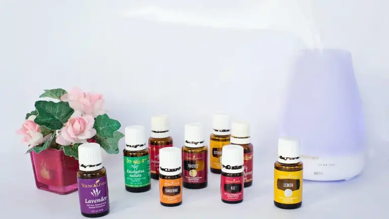 Assorted essential oil bottles arranged on a surface with a white diffuser in the background.