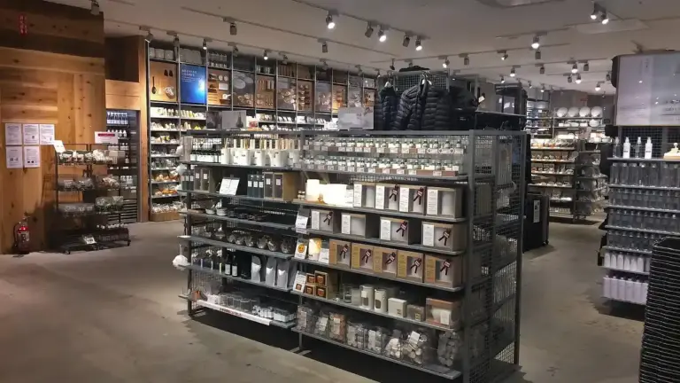 Interior of an essential oils shop with metal display racks and wooden shelves filled with bottles and boxes of diffusers and oils, warm lighting.