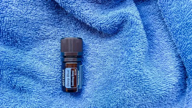 Small dark blue bottle of essential oil resting on a textured blue towel
