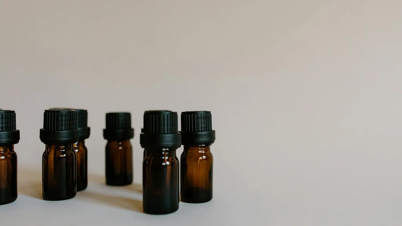 Amber glass essential oil bottles with black caps arranged on a pale surface.
