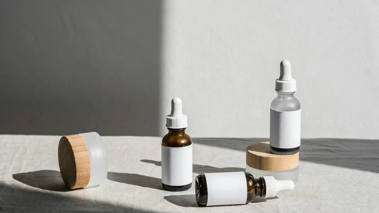 Amber essential oil bottles with glass droppers and wooden caps arranged on a light gray concrete surface.