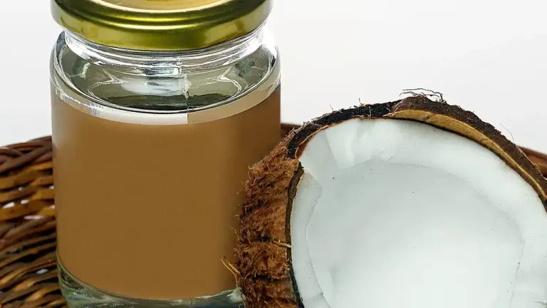 Jar of fish oil next to a halved coconut on a wooden surface