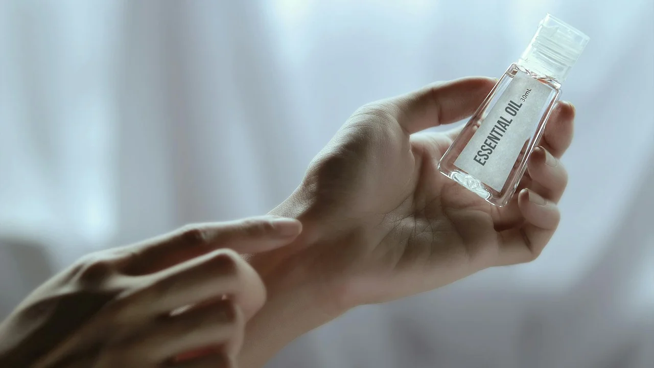 Close-up of hands holding a small bottle labeled Essential Oil