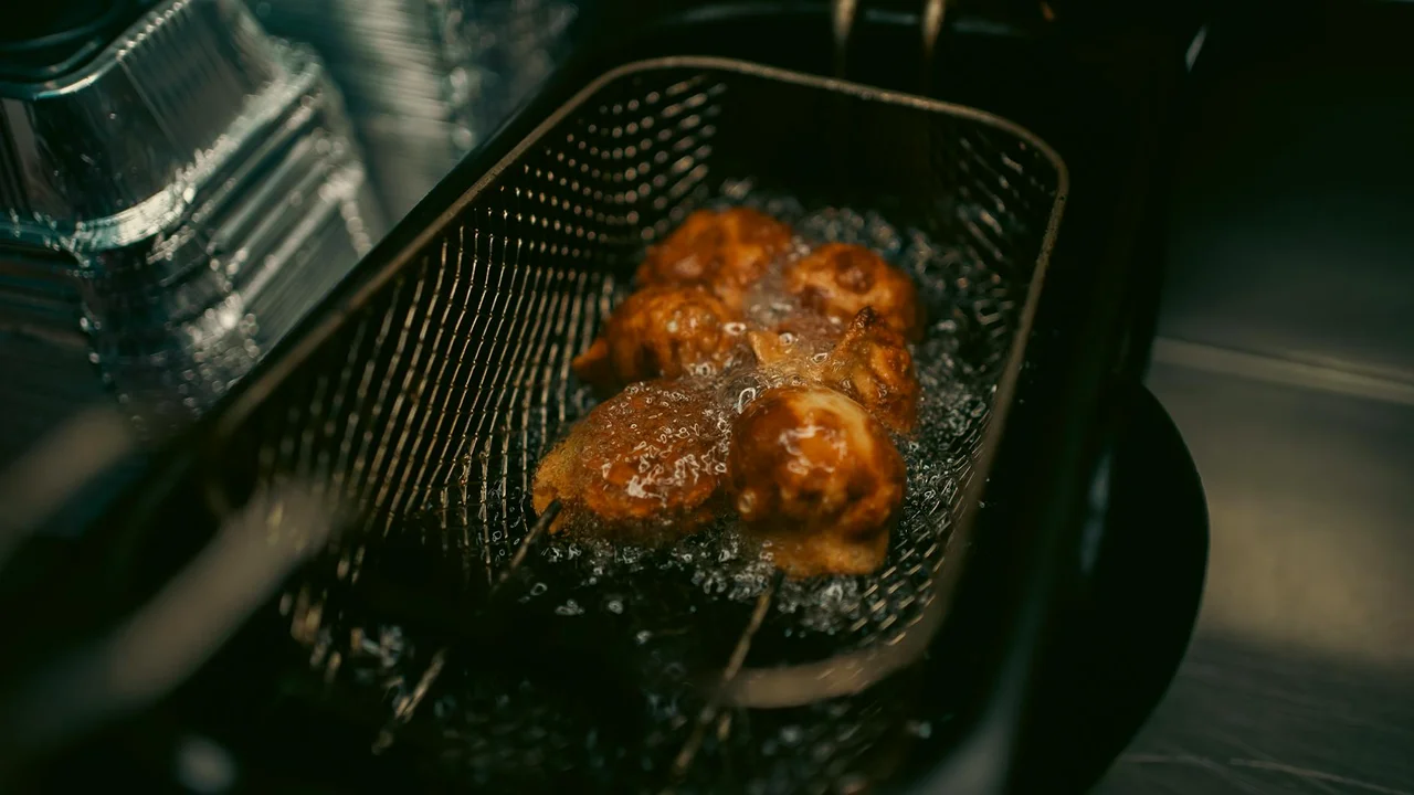 Food being fried in a metal basket submerged in hot oil