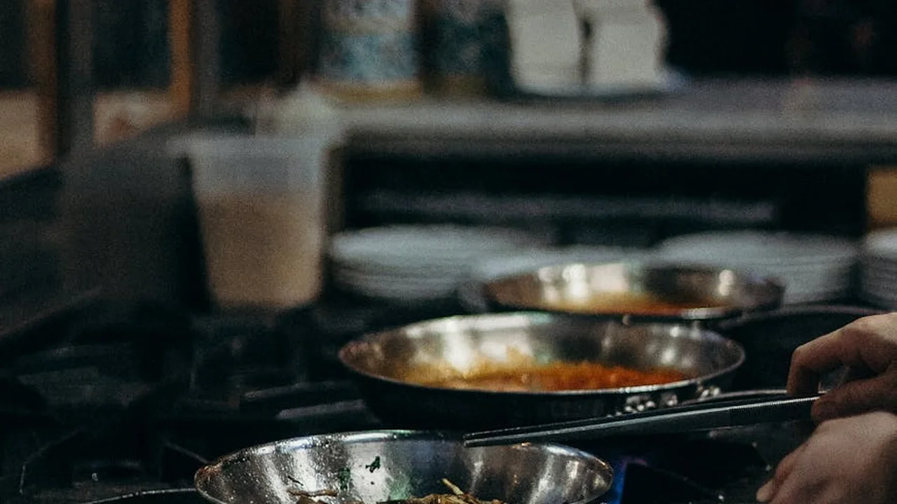 Hands near hot frying pans on a stove, illustrating heat, oil, and the need for caution when frying