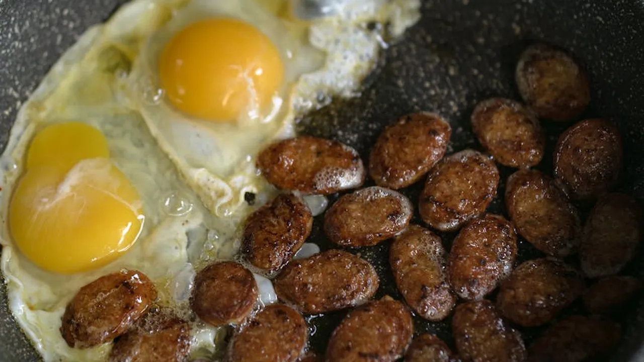 Two sunny-side-up eggs frying in a pan with numerous small browned fried morsels nearby