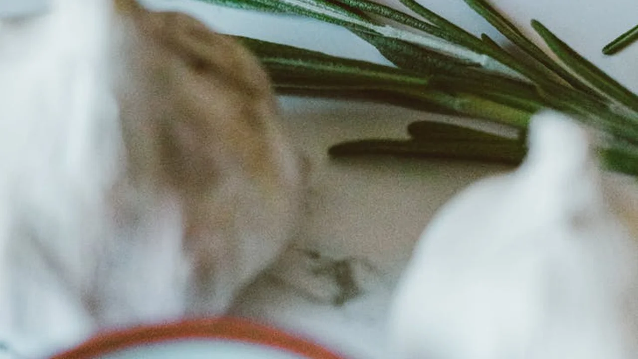 Close-up of garlic bulbs and fresh rosemary on a light surface