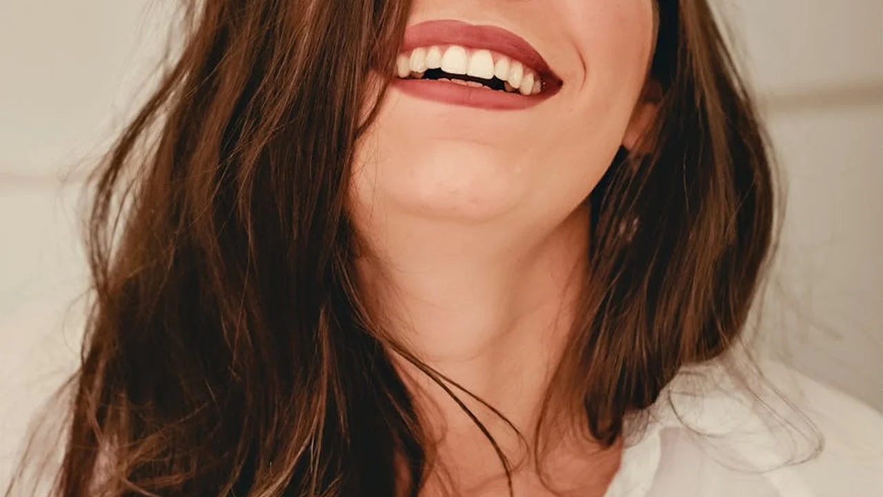 Close-up of a person with long brown hair and a bright smile