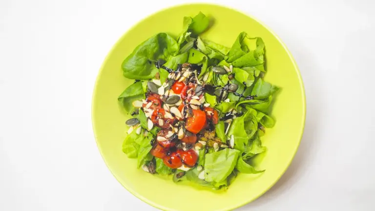 Lime green bowl filled with a fresh salad of mixed greens and cherry tomatoes.