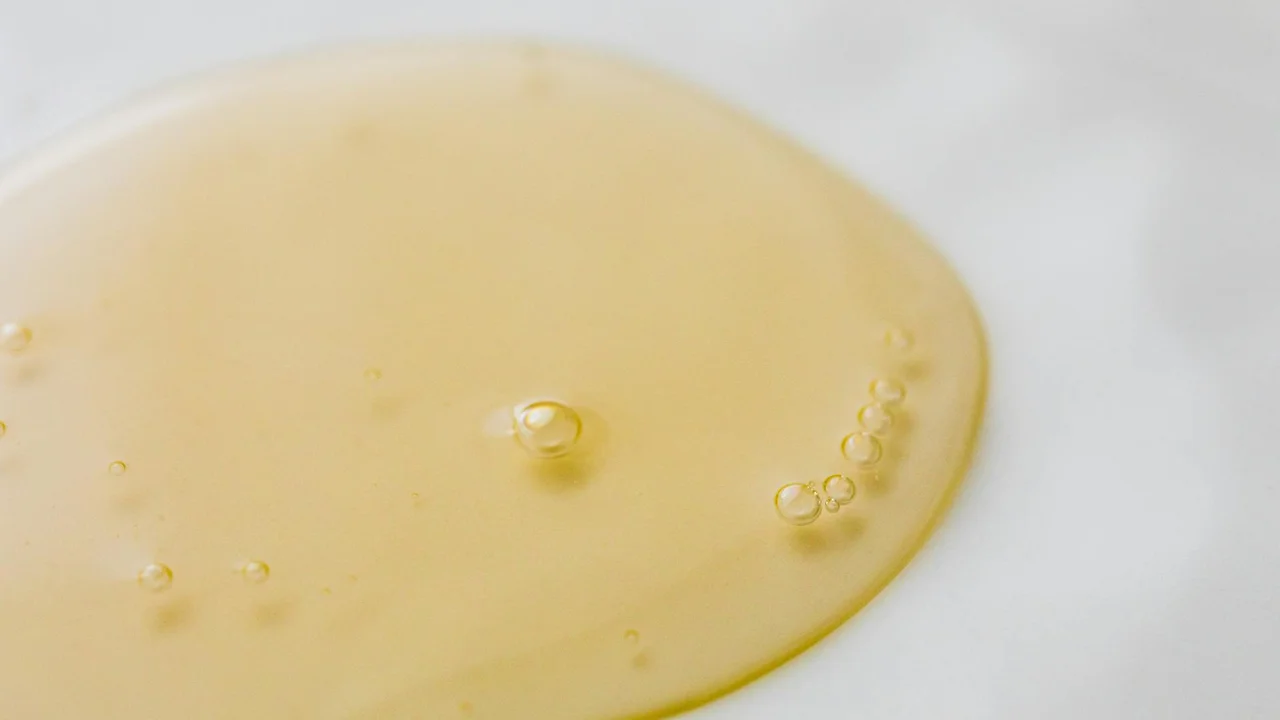 Close-up of golden hair oil on a marble surface, ready for an application ritual.