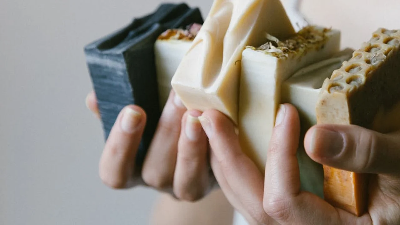 Hands holding a row of colorful soap bars, showcasing products made with shea butter.
