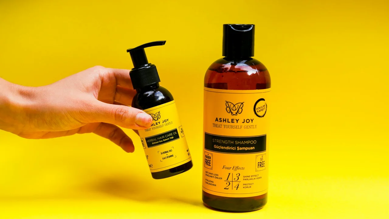 Small pump bottle and larger bottle of Ashley Joy hair care products on a bright yellow background, representing overnight hair oil treatment.