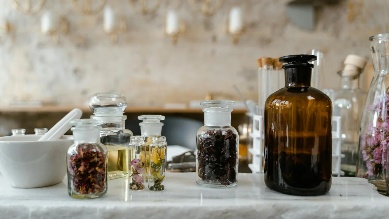 Assorted glass bottles containing essential oils on a laboratory bench with a large amber bottle in the background.