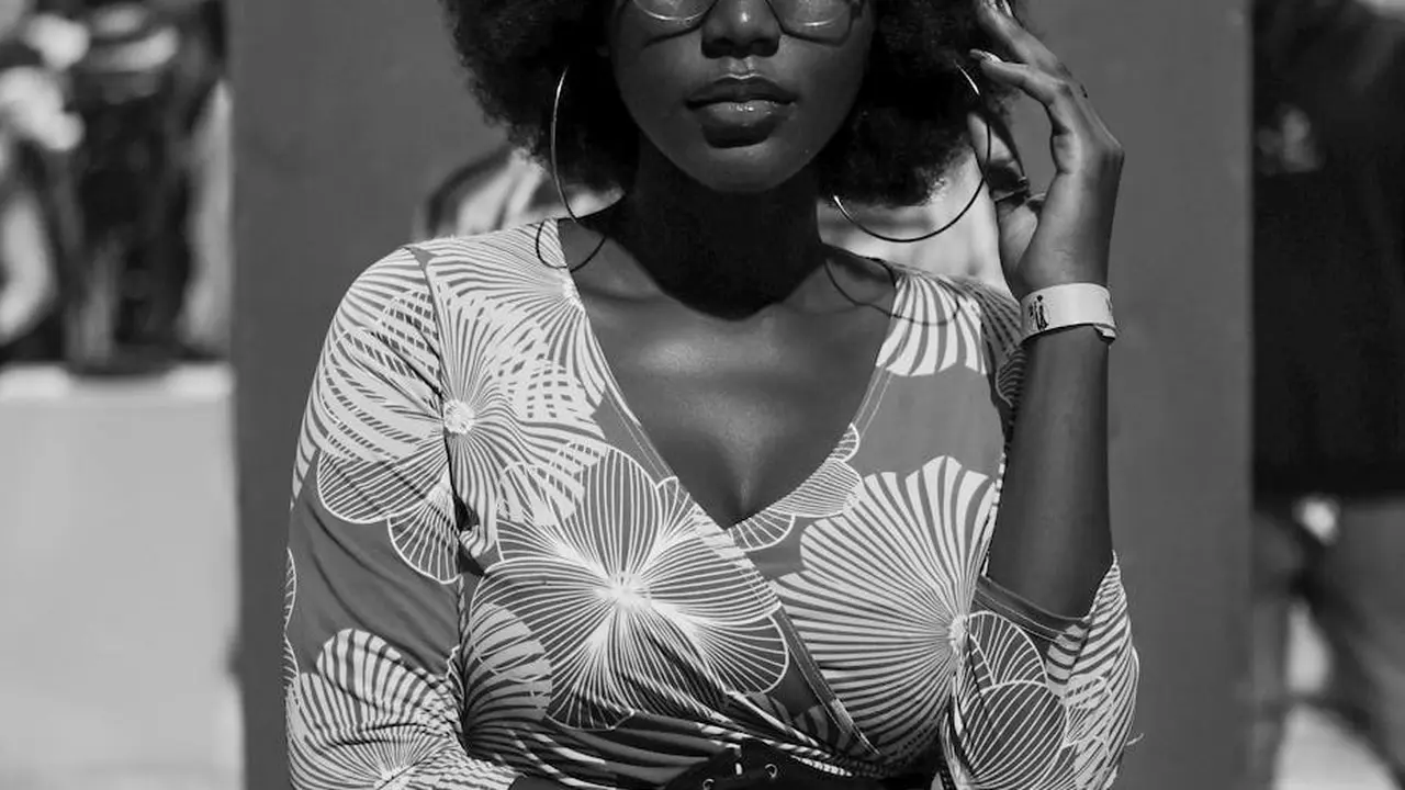 A stylish woman wearing a patterned dress and sunglasses outdoors