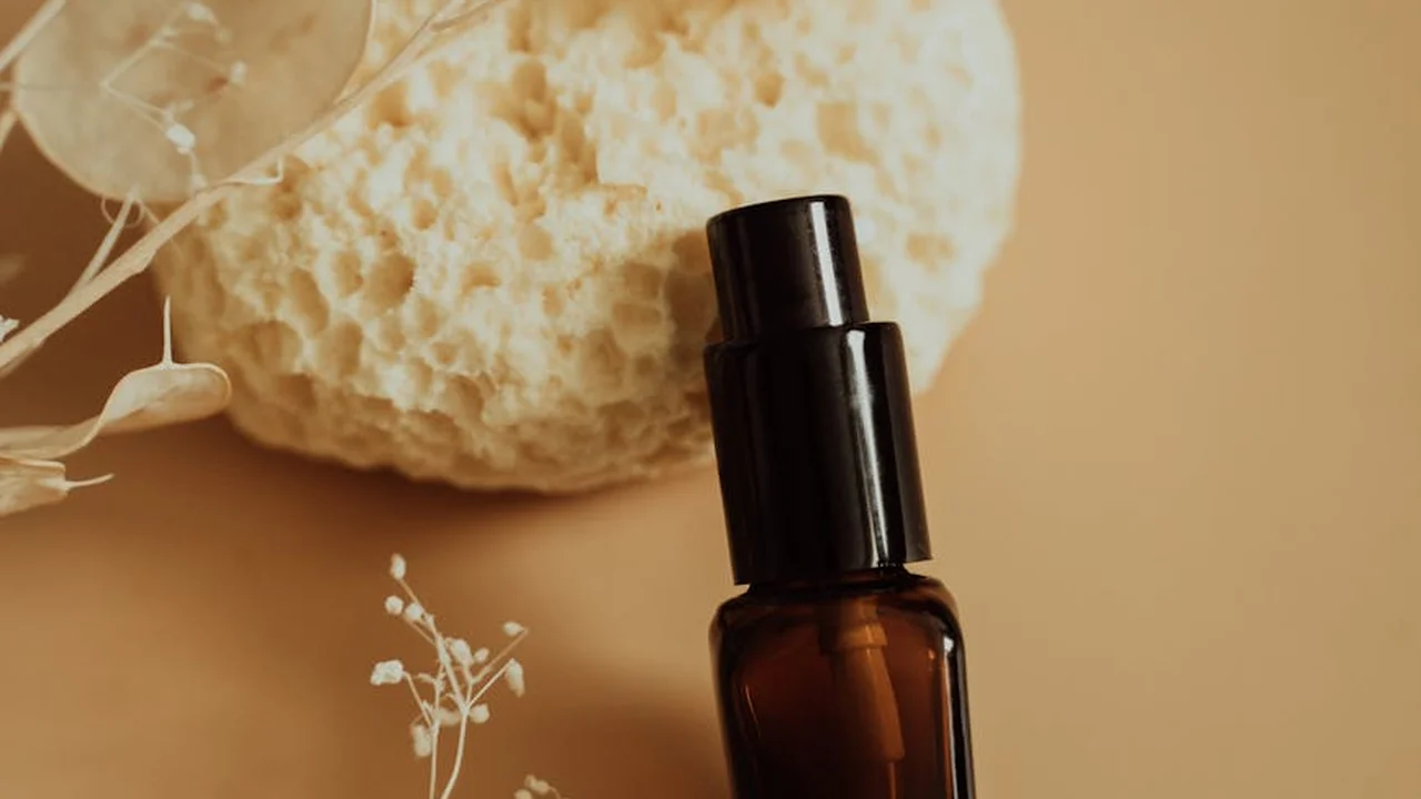 Amber glass bottle of lavender essential oil with a black cap on a soft beige background