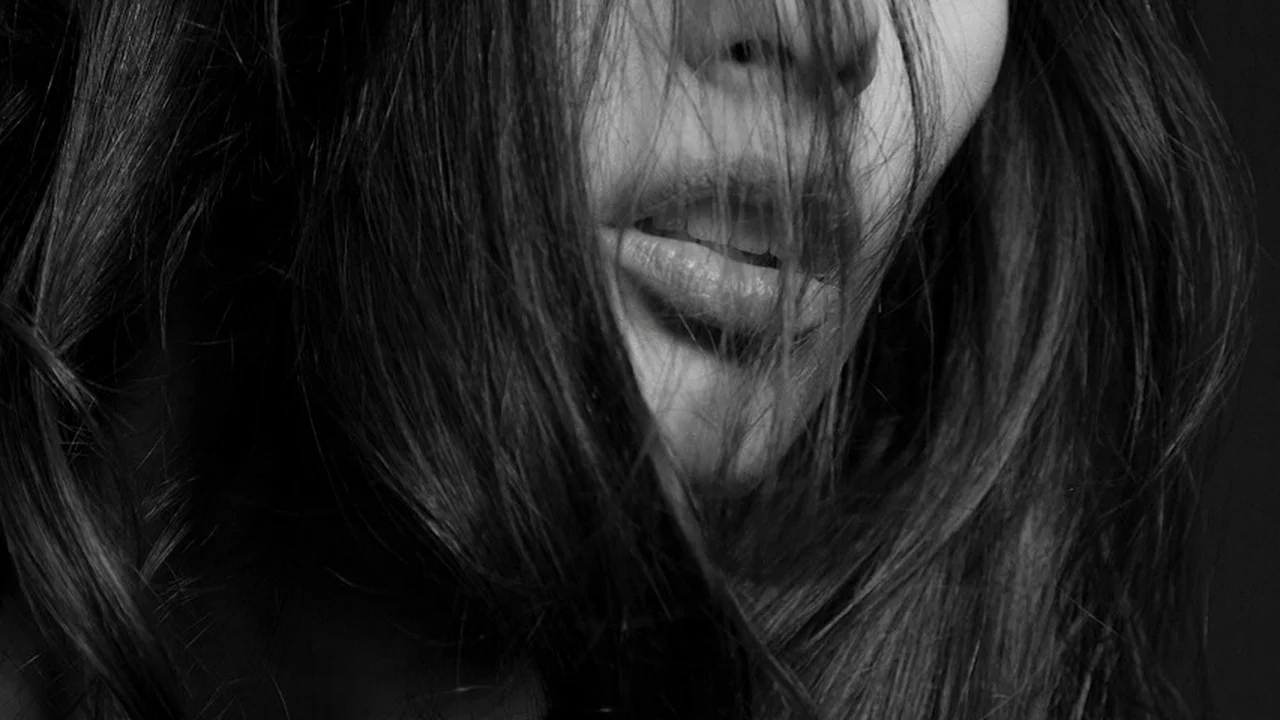 Close-up black-and-white photo of a person with hair partially covering the face