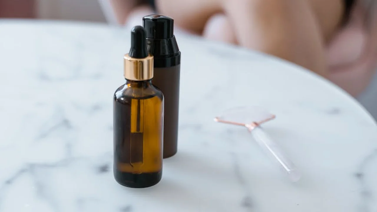 Amber glass bottles with dropper on a marble surface, used for applying linseed or tung oil, with a small glass spreader in the background.