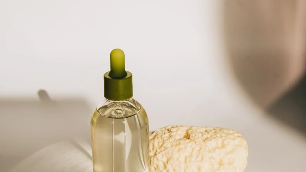 Close-up of a mink oil bottle with a dropper beside a beige cloth, prepared for boot and leather care.