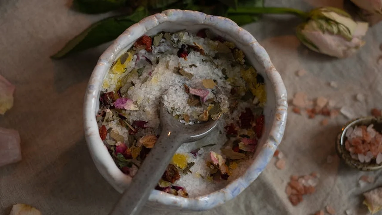 White ceramic mortar filled with a colorful mix of herbs and flower petals, with a spoon resting inside, placed on a neutral surface.