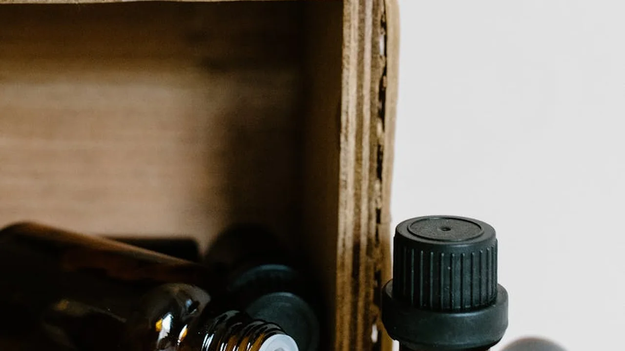 Assorted dark glass bottles with a black cap inside a cardboard box, prepared for neem oil-based pest control in a garden toolkit.