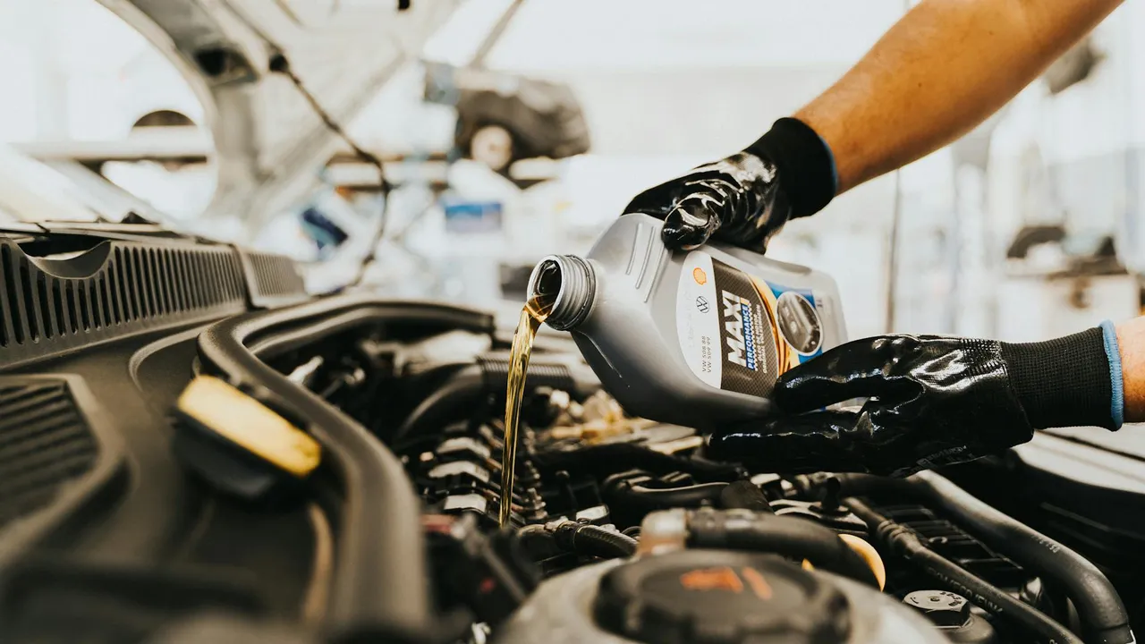 Gloved hand pouring motor oil into a car engine