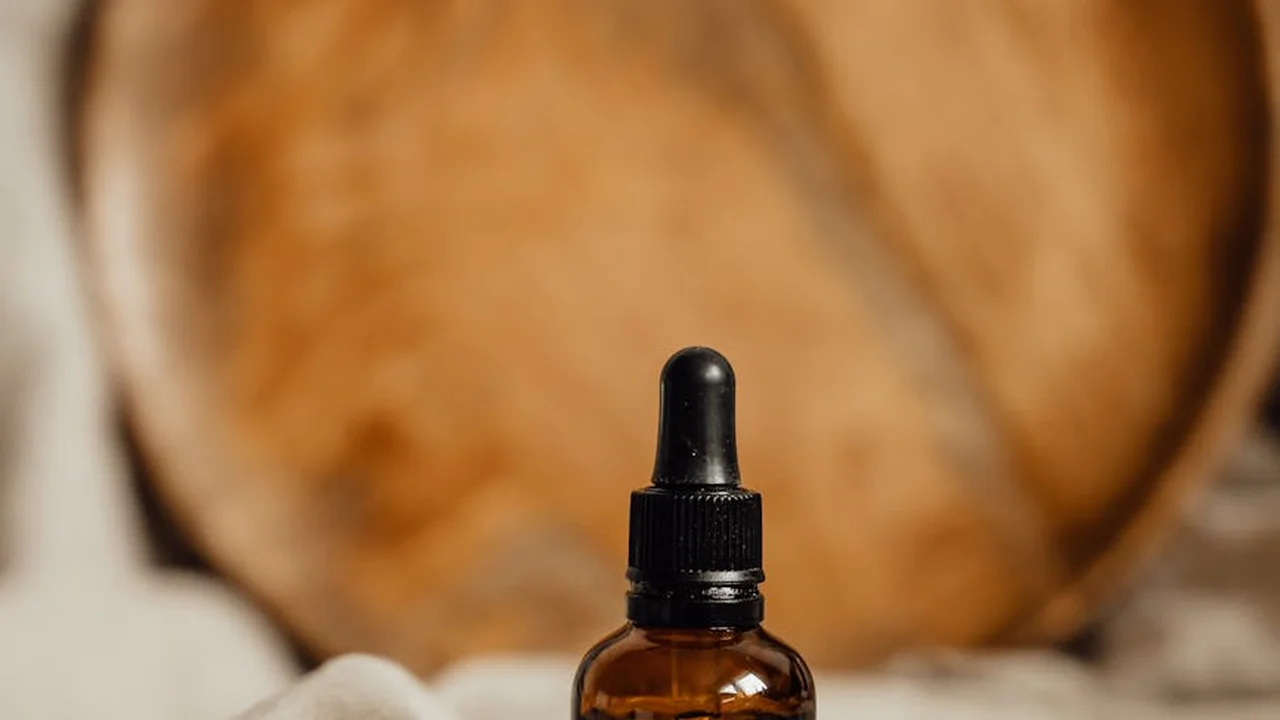 Dropper bottle of oil in the foreground with a blurred loaf of bread in the background