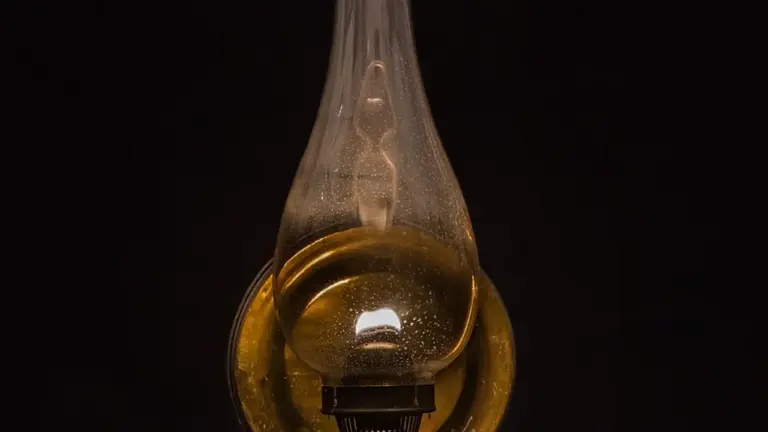 Close-up of a glass bottle filled with golden oil against a dark background.