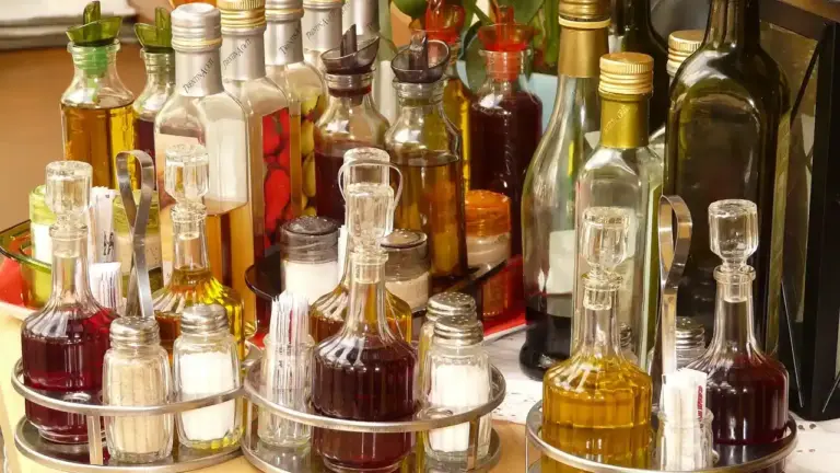 Assorted glass bottles of cooking oil in a shop display, illustrating the variety of oils used in food preparation.
