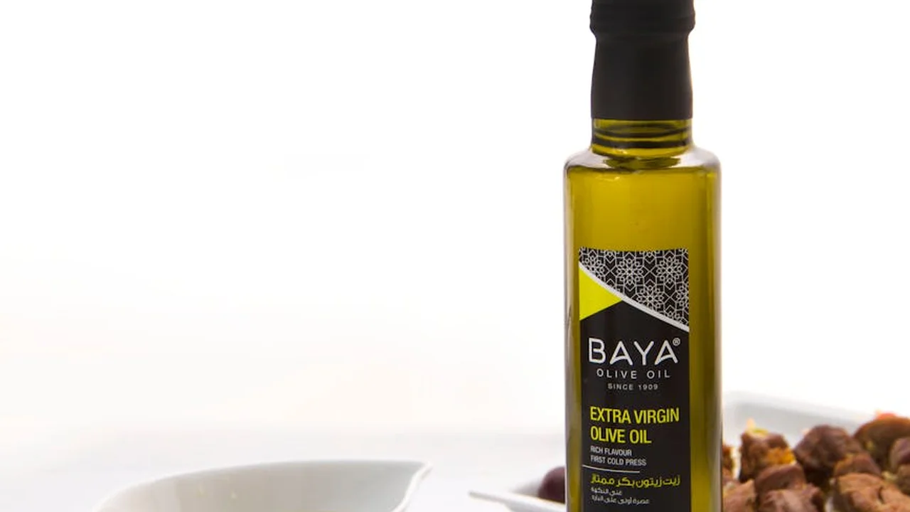 Bottle of extra-virgin olive oil with nuts on a white background